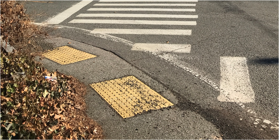 Figure 9 - Northwest Intersection Pedestrian Facilities. Image shows aerial view of two crosswalks meeting on the street corner where there are two pedestrian detectable warning strips and the sidewalk is made of pavement.